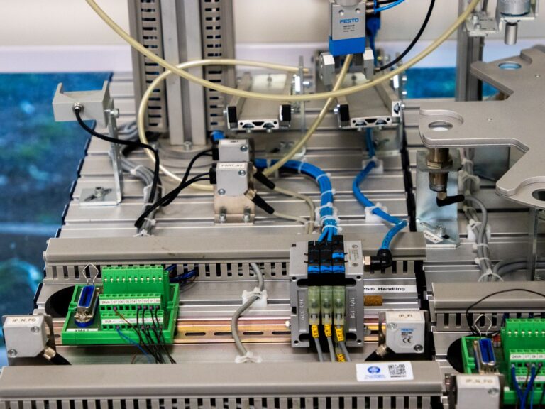 Close-up de equipamentos industriais exibindo fiação eletrônica e sensores em um ambiente de manufatura.